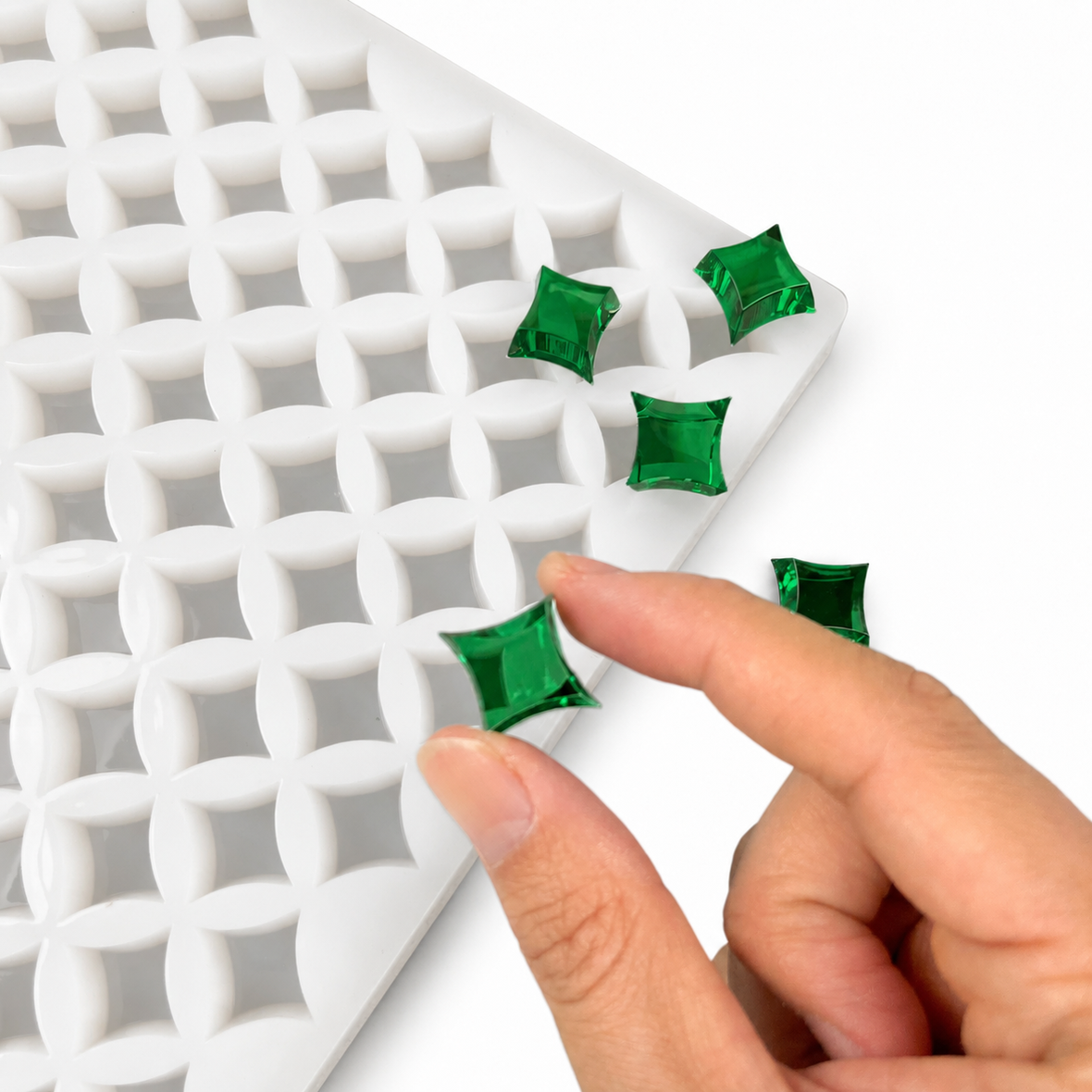 Hand drückt einen fertigen smaragdgrünen sternförmigen Fruchtgummi in einer flexiblen Silikonform