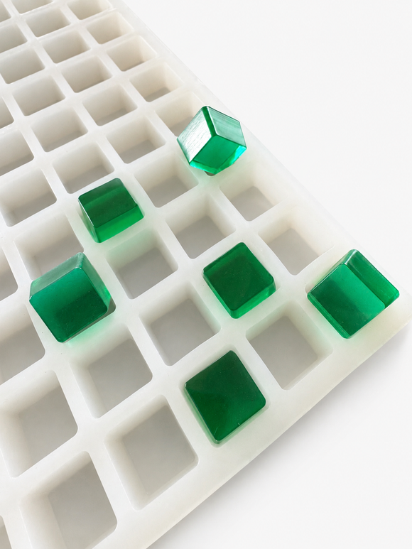 Detailed product view of a 2.85mL cube gummy mold with 315 cavities and finished emerald green gummy cubes