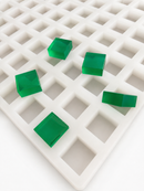 Close-up of 4mL Square Gummy Mold - 100 Cavities with translucent emerald green square gummies on a white background